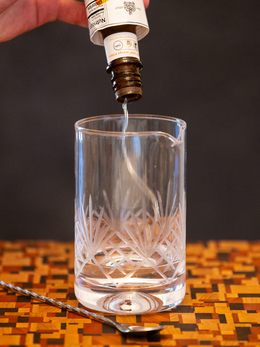 Dashing bitters into a stirring glass