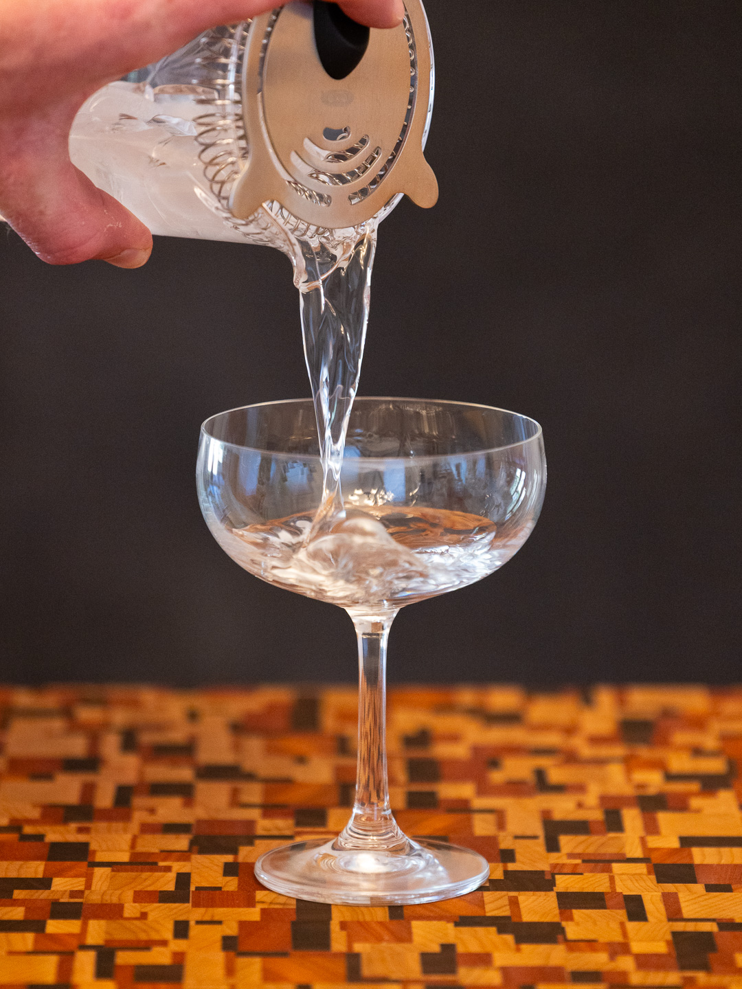 Straining the cocktail into a coupe glass