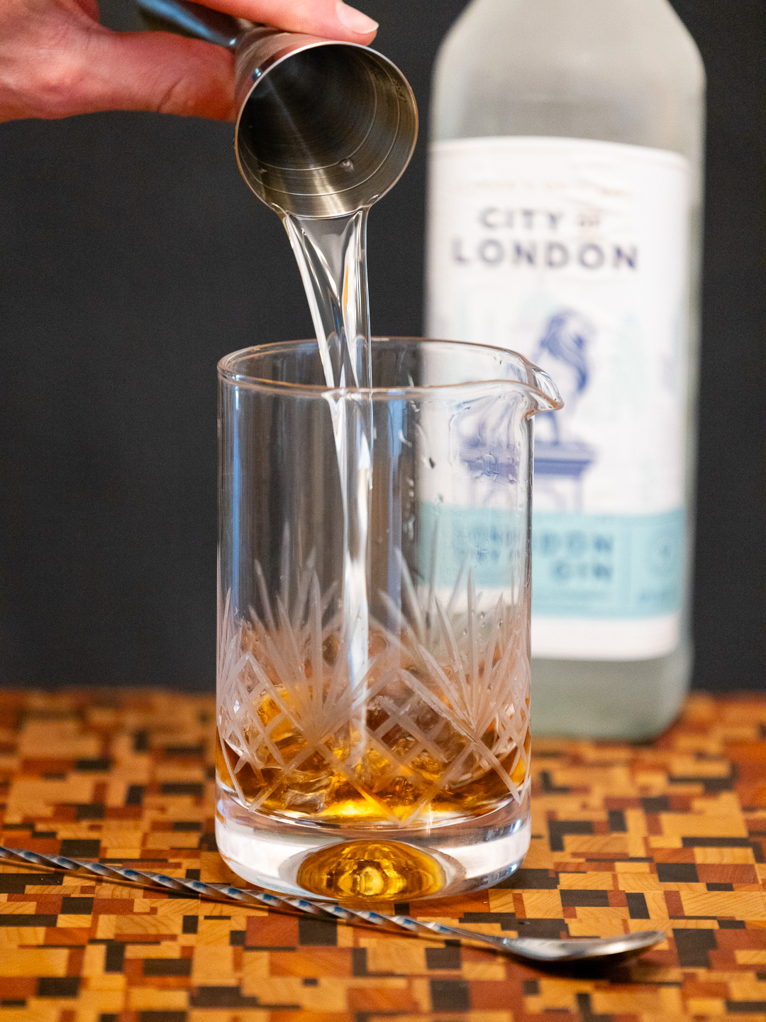 Pouring old tom gin into a mixing glass