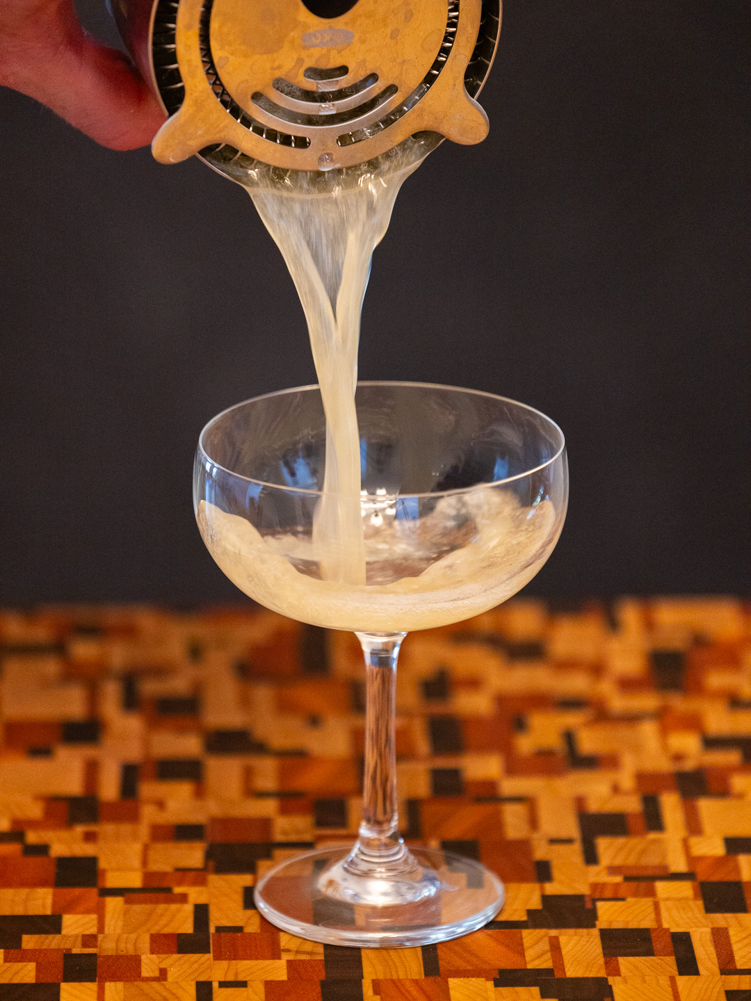 Straining the cocktail into a coupe glass