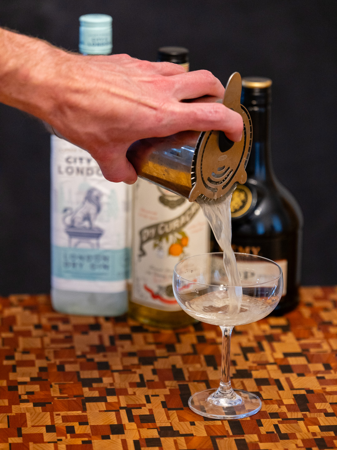 Straining the cocktail into a coupe glass