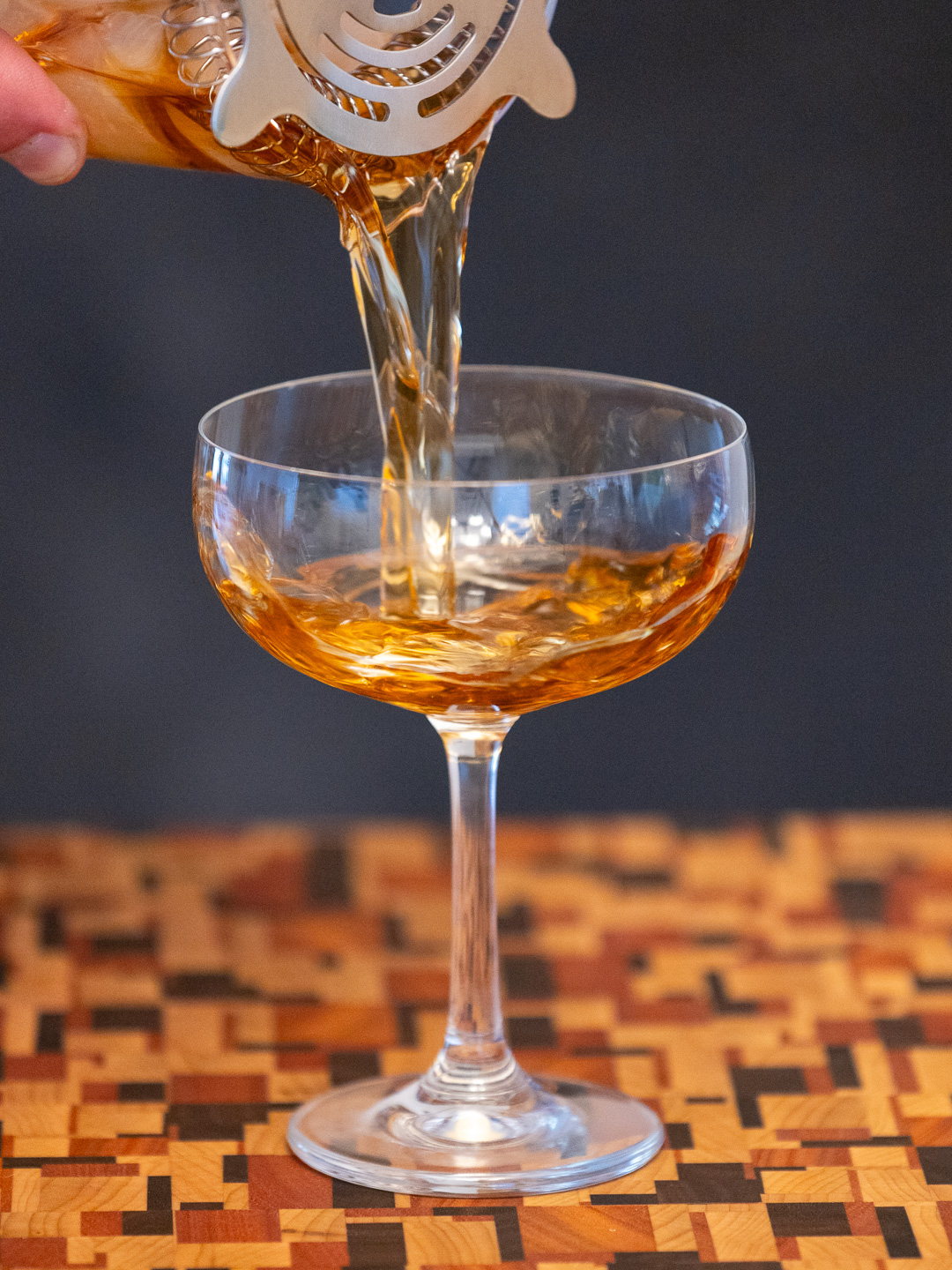 Pouring the Black Rumhattan into a coupe glass