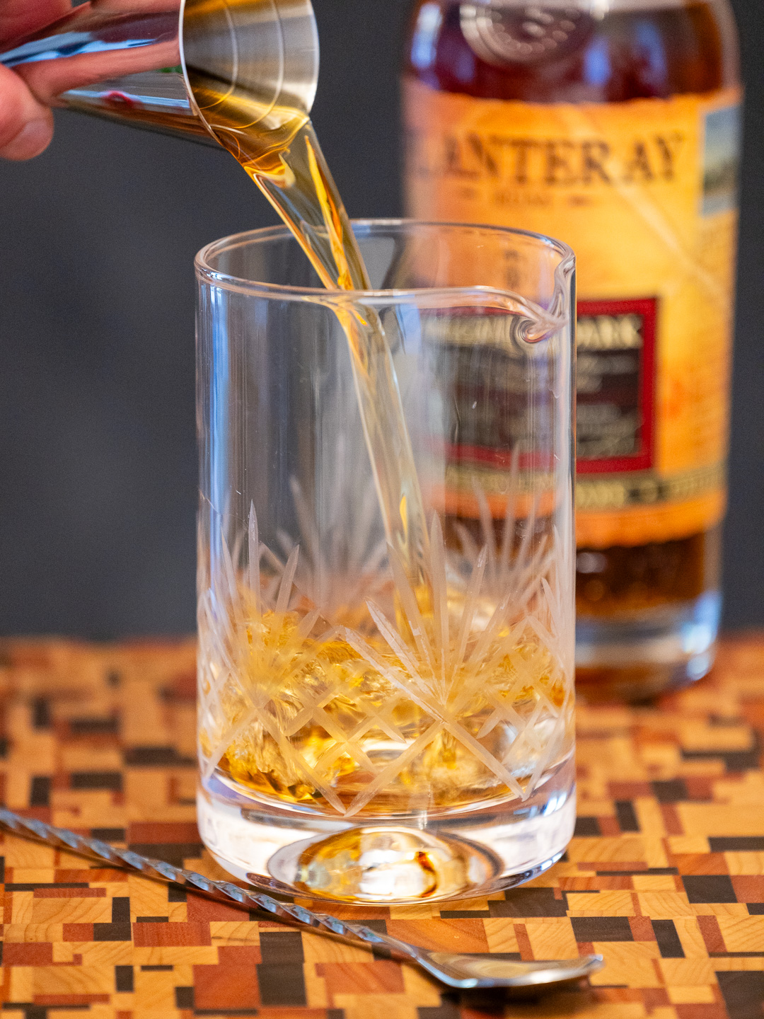 Pouring dark rum into a mixing glass