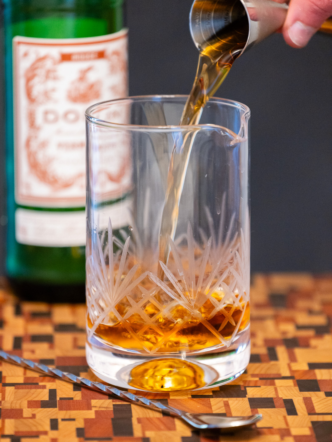 Pouring sweet vermouth into a mixing glass