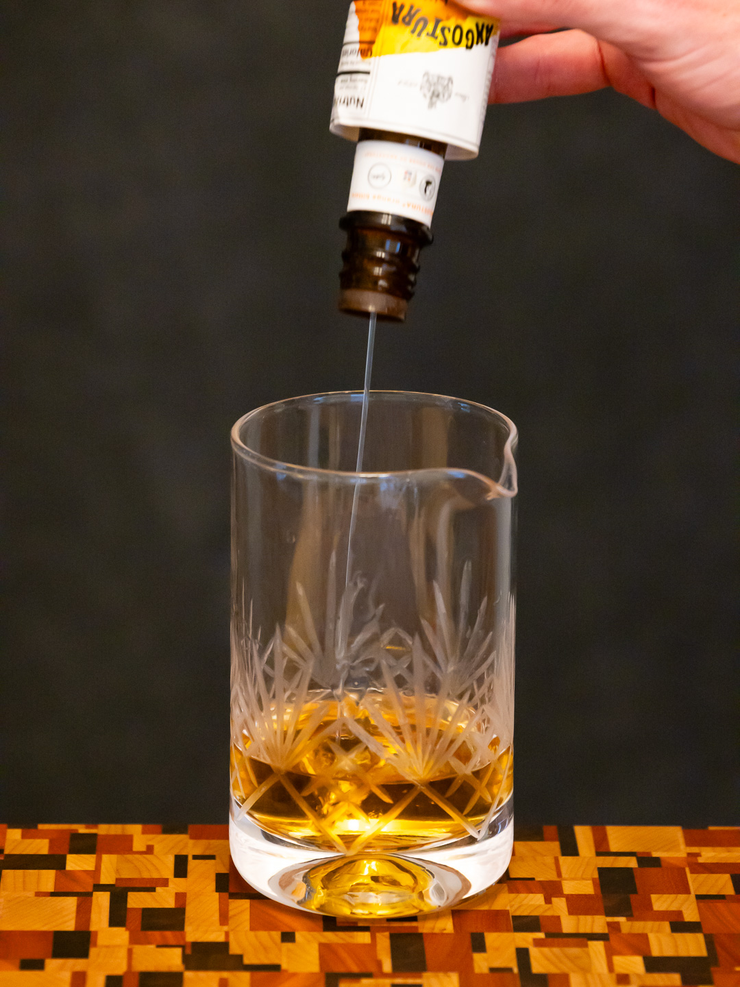 Adding orange bitters to a mixing glass