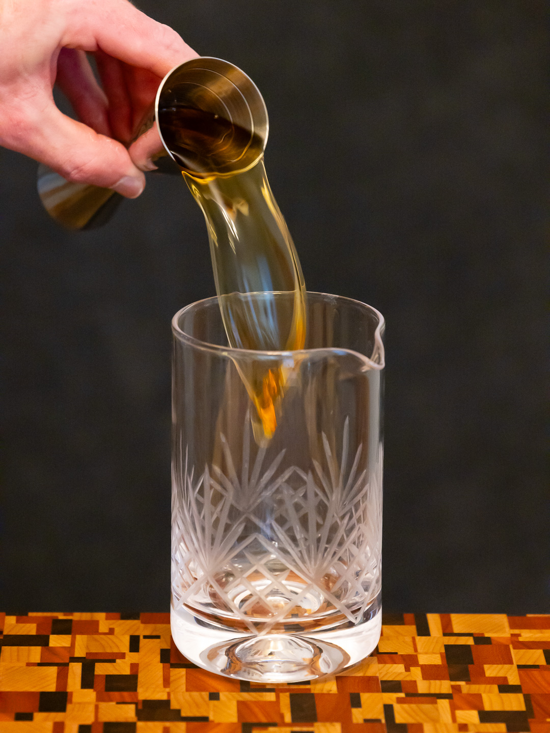 Pouring bourbon into a mixing glass