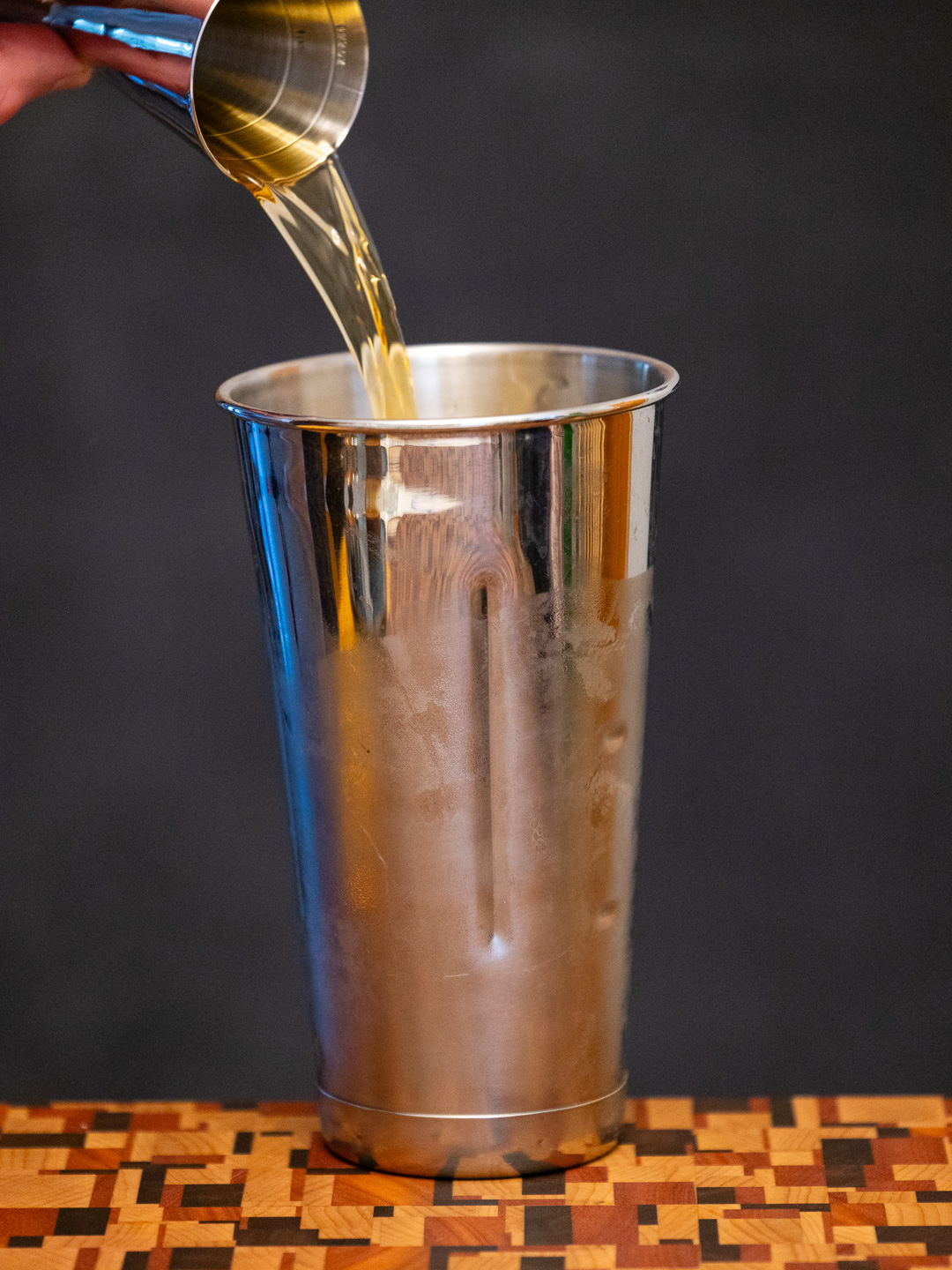 Pouring bourbon into a mixing tin