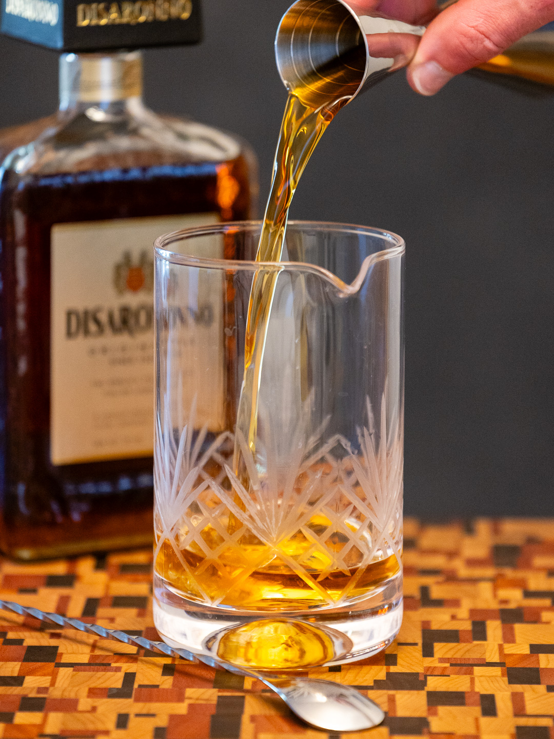 Pouring amaretto into a mixing glass