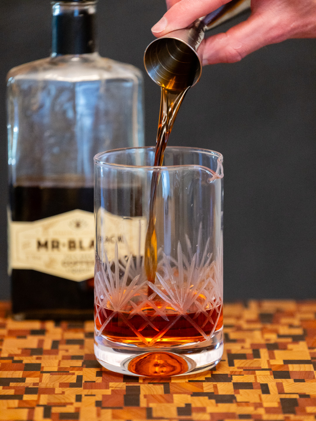 Pouring coffee liqueur into a mixing glass