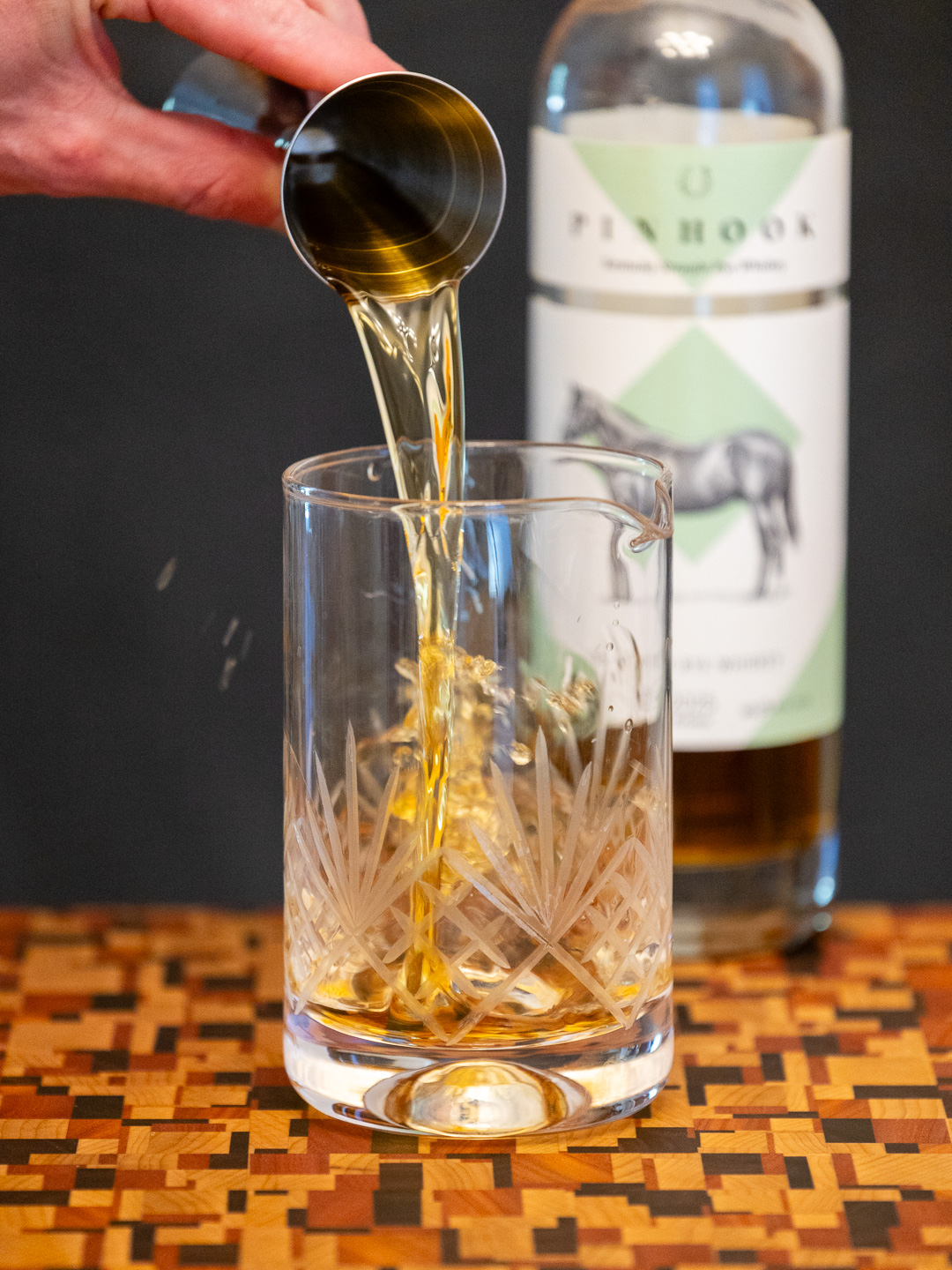 Pouring rye whiskey into a mixing glass
