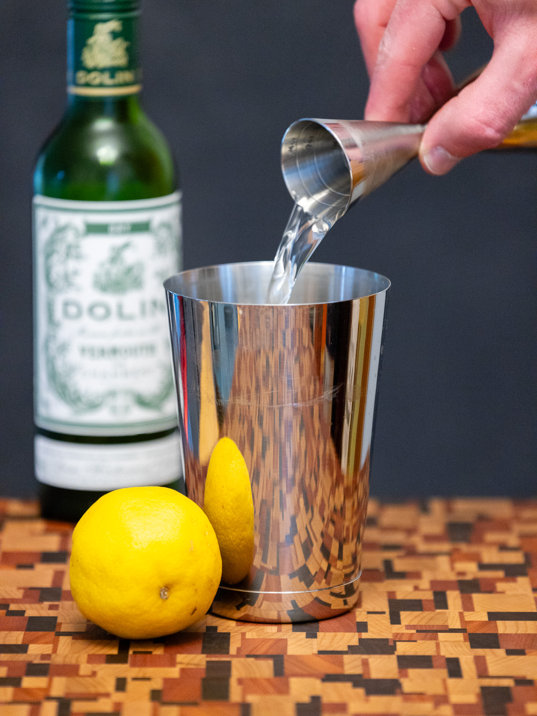 Pouring dry vermouth into a cocktail shaker