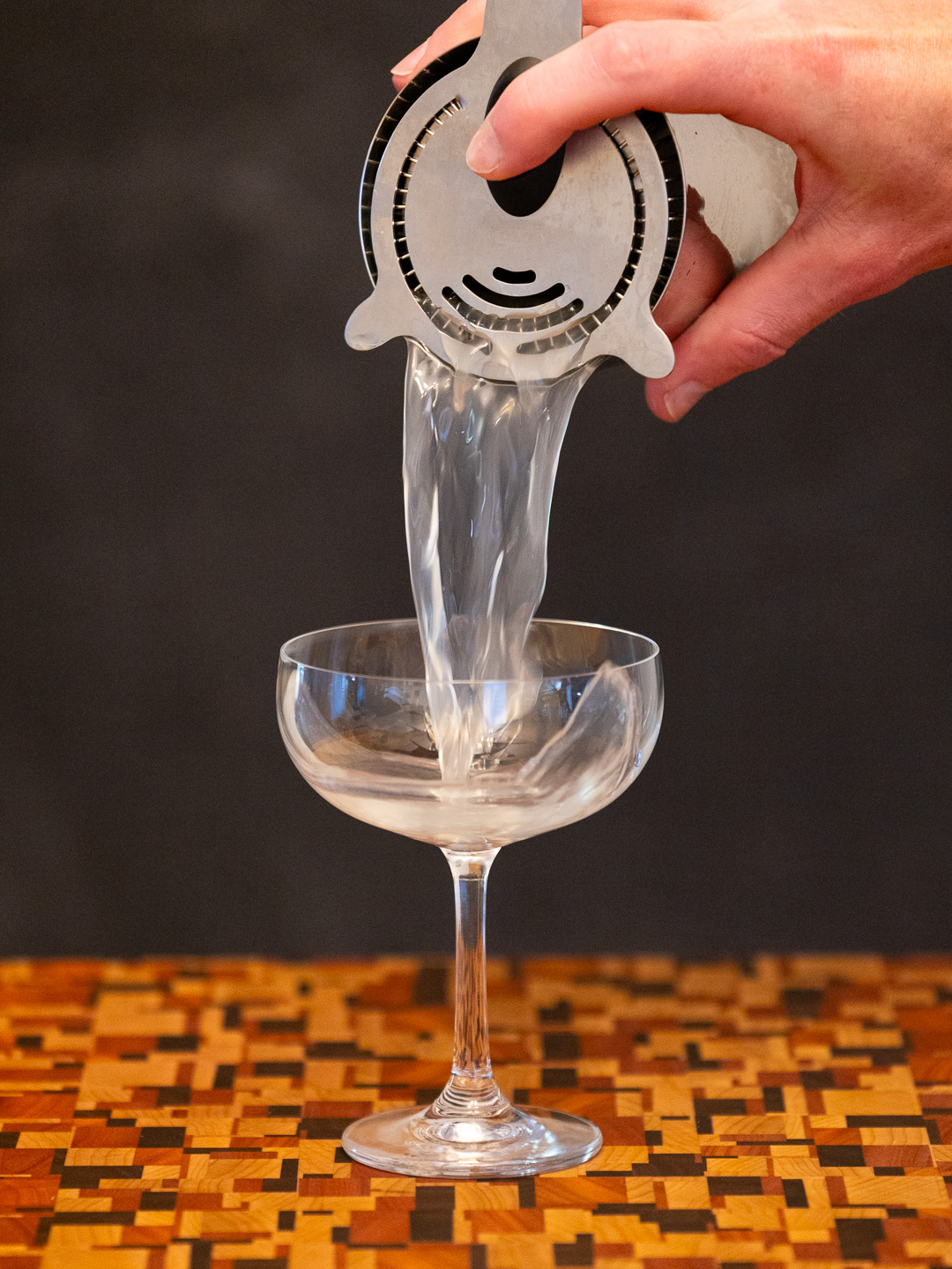 Straining the cocktail into a coupe glass