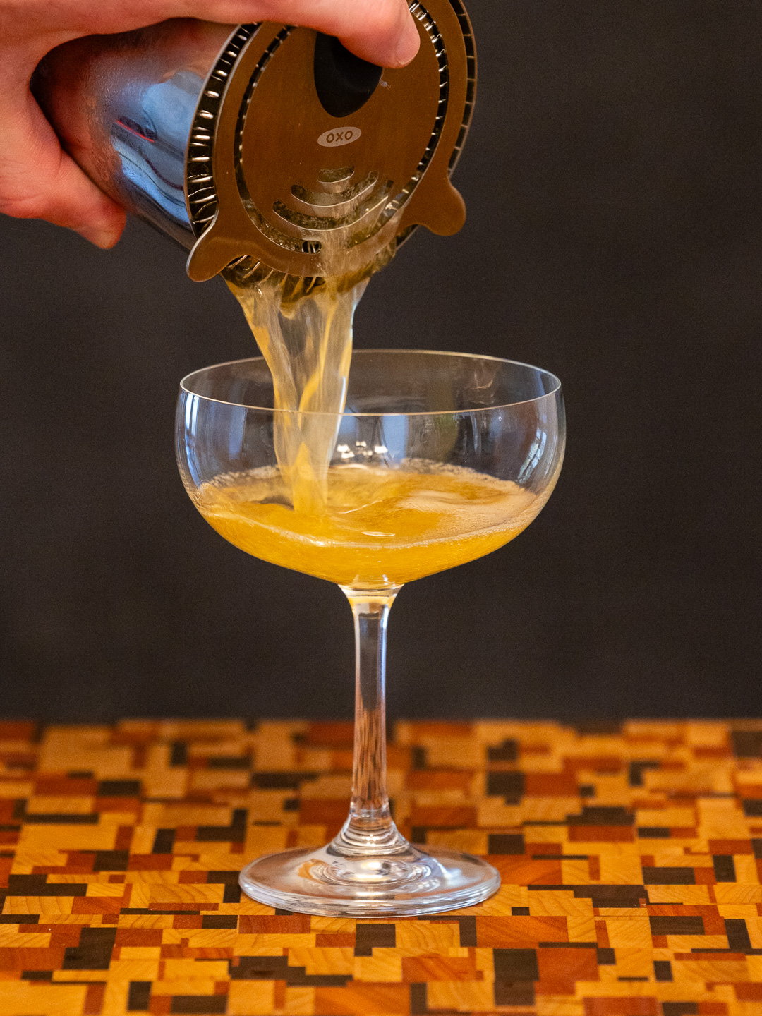 Straining the cocktail into a coupe glass