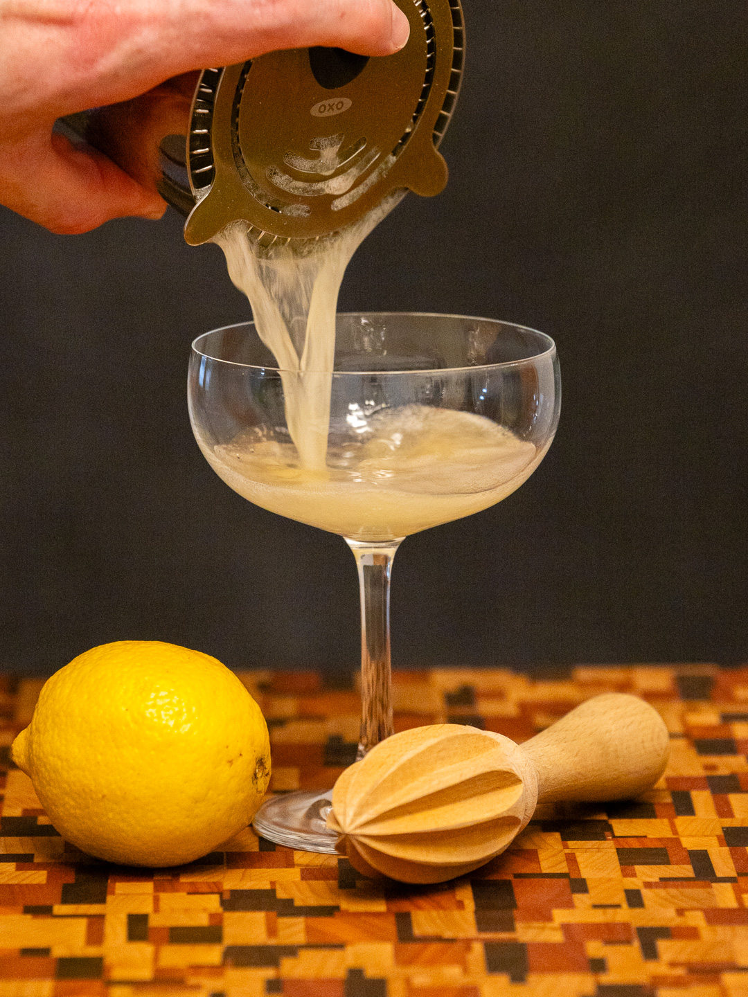 Straining the cocktail into a coupe glass