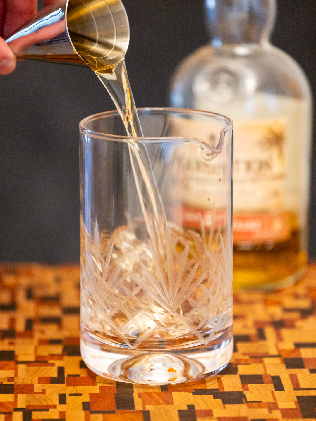 Pouring gold rum into a mixing glass