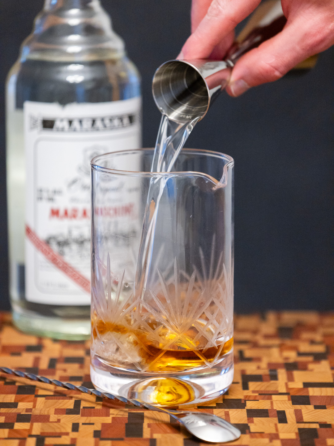 Pouring maraschino liqueur into a mixing glass