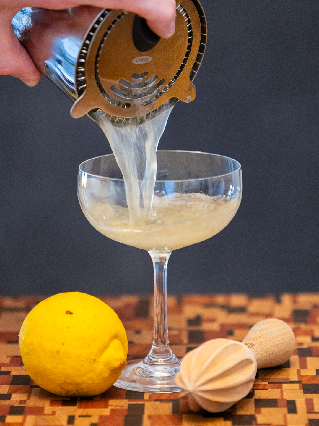 Straining the cocktail into a coupe glass