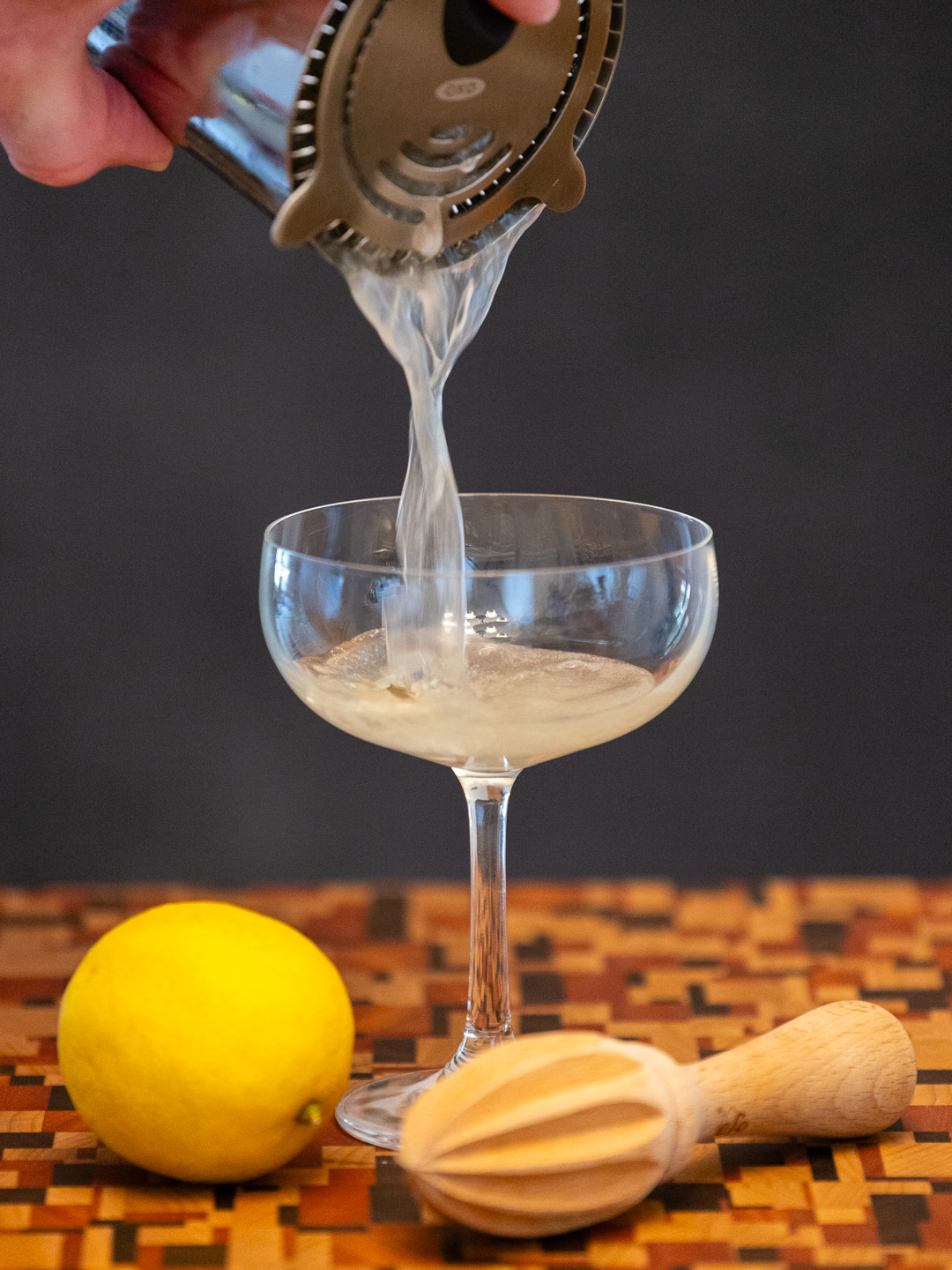 Straining the cocktail into a coupe glass