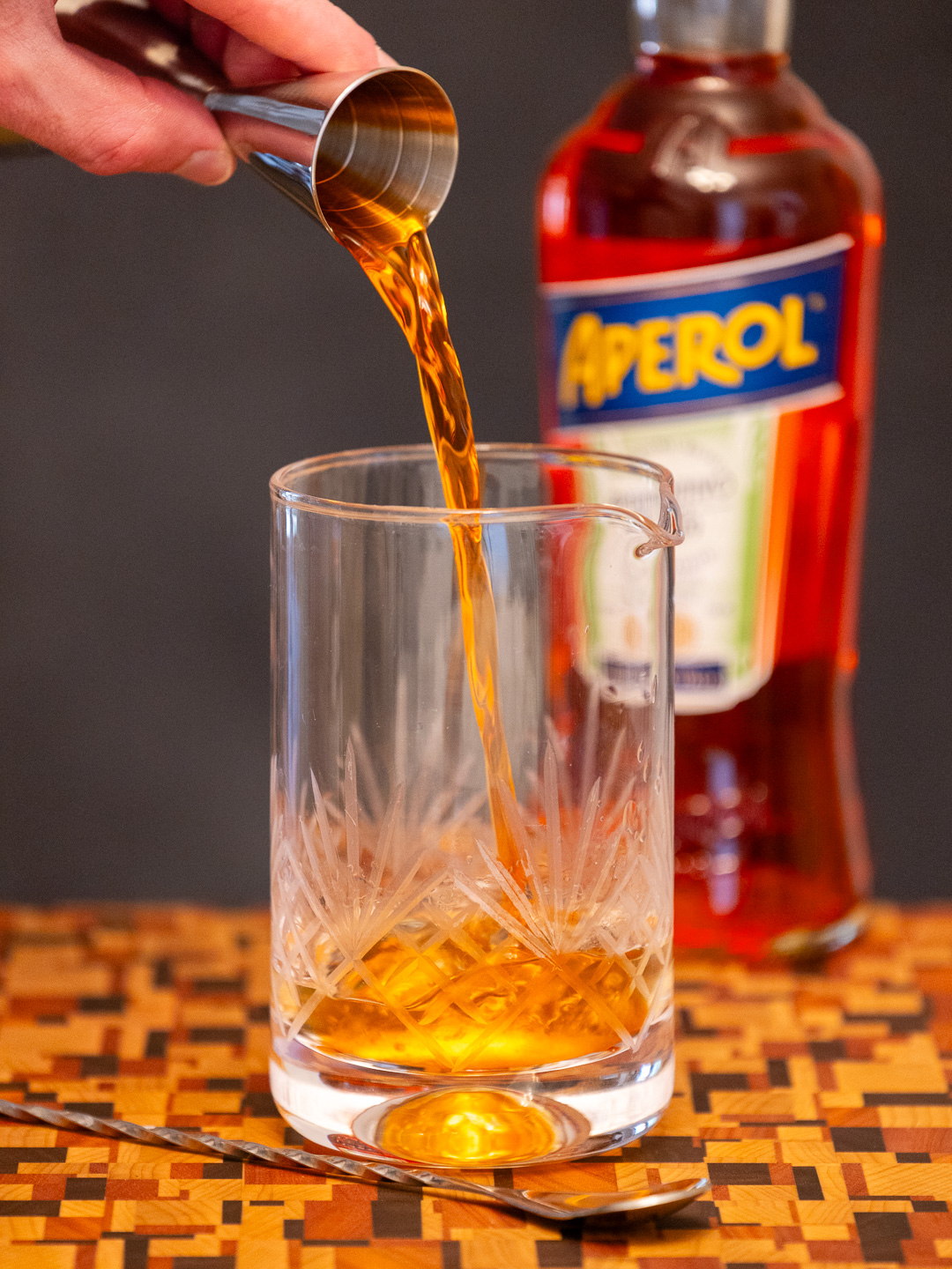 Pouring Aperol into a mixing glass