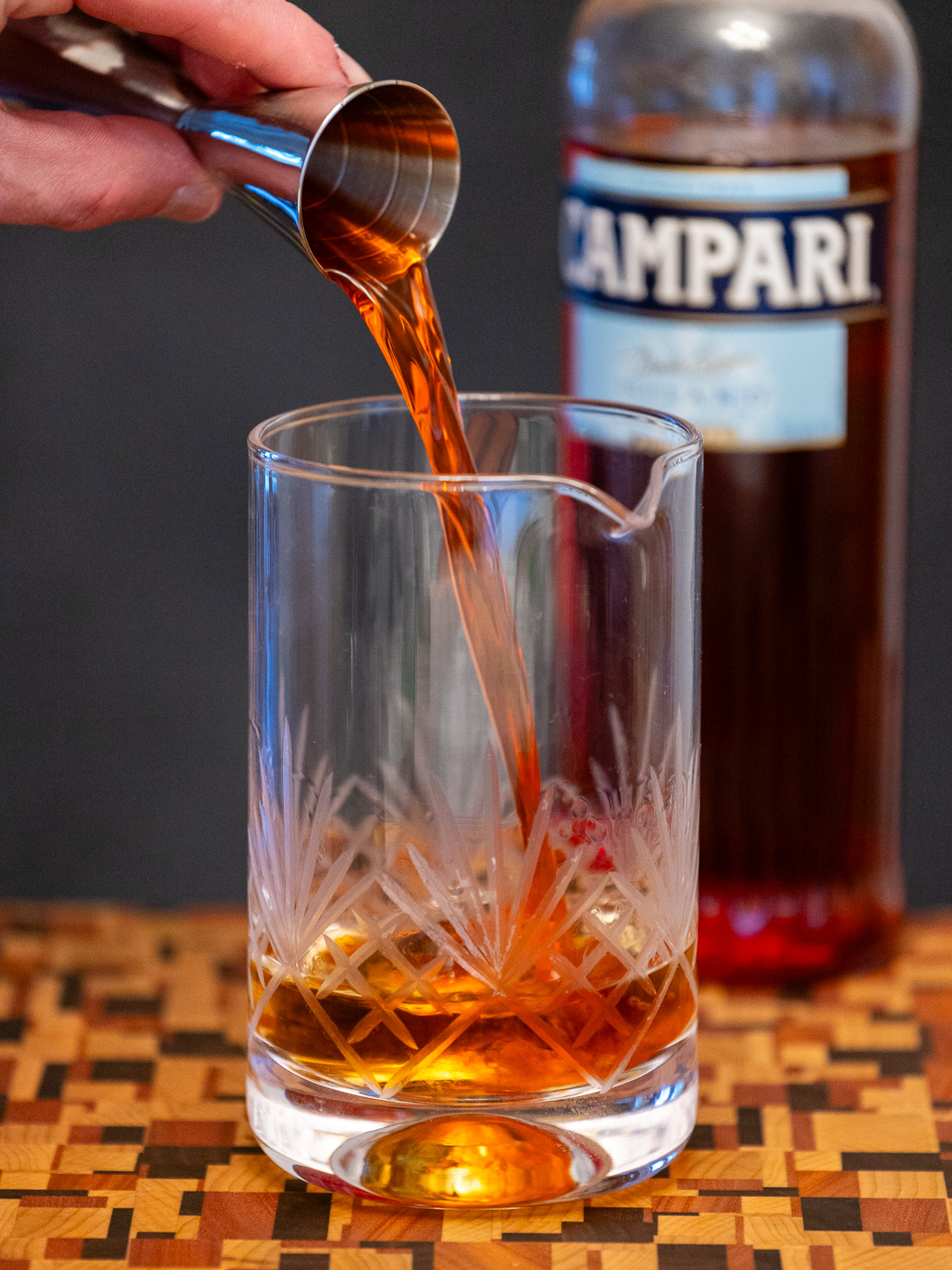 Pouring Campari into a mixing glass
