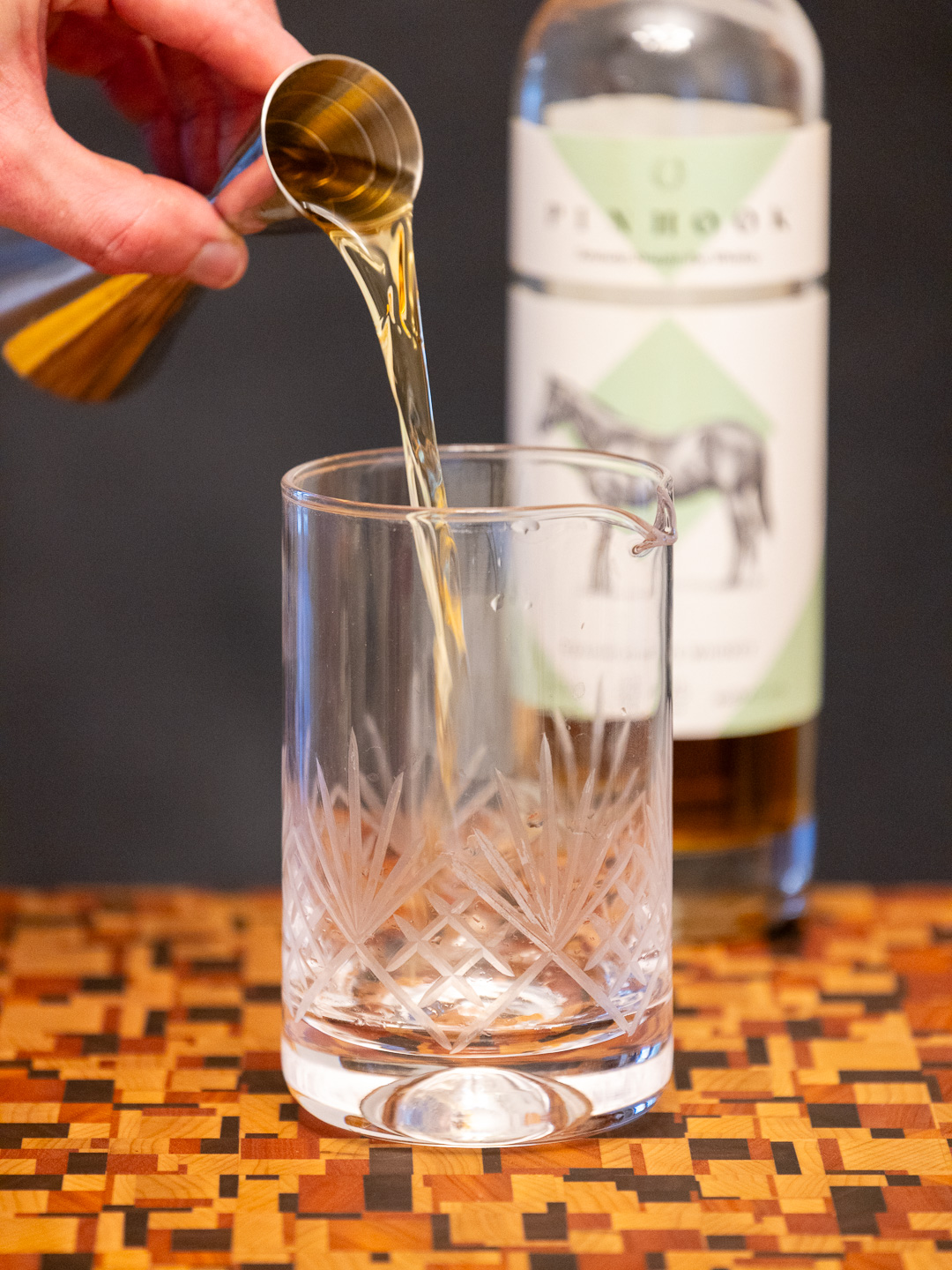 Pouring rye whiskey into a mixing glass